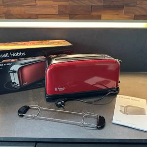 Der Russell Hobbs Colours Flame Red steht mit Zubehör und Karton auf einer Küchenarbeitsplatte.