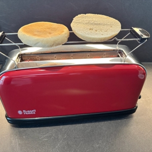 Ein geschnittenes Brötchen liegt im dafür vorgesehenem Aufsatz im Russell Hobbs Colours Flame Red