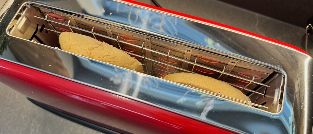 Ein geschnittenes Brötchen wird im Russell Hobbs Colours Flame Red getoastet.