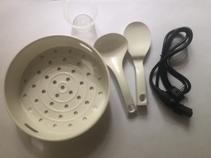 Zubehör für einen Multikocher liegt nebeneinander, wie Löffel, Einsatz und Messbecher.