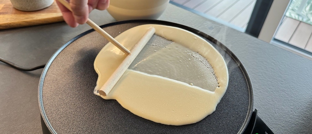 Eine Hand beginnt, Teig auf dem Russell-Hobbs-Fiesta-Crêpes-Maker zu verteilen