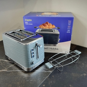 Der getestete Toaster von Russell Hobbs steht mit der Verpackung und dem Zubehör auf einer dunklen Arbeitsfläche.