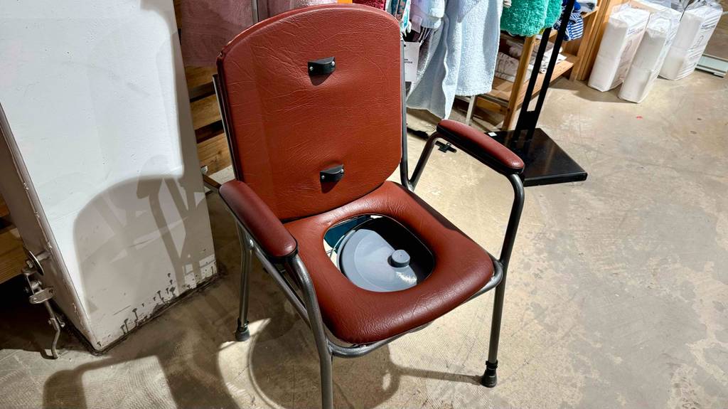 Ein brauner Toilettenstuhl im Test steht in einem Verkaufsbereich.