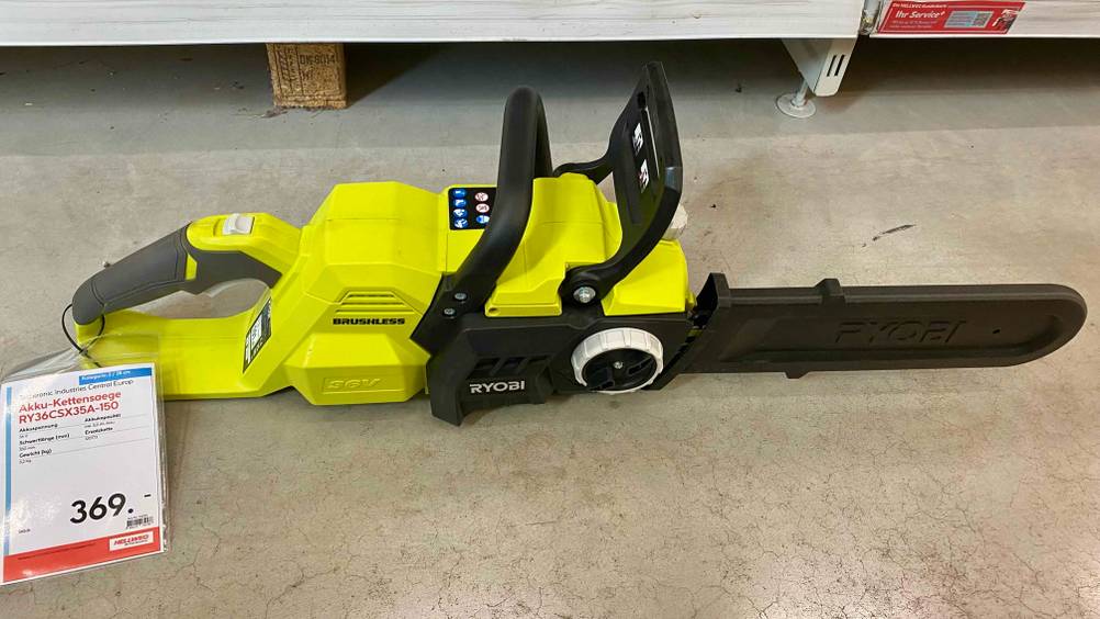 Im Test: Eine Akku-Kettensäge von oben auf einem Betonboden liegend mit Preisschild am Griff.