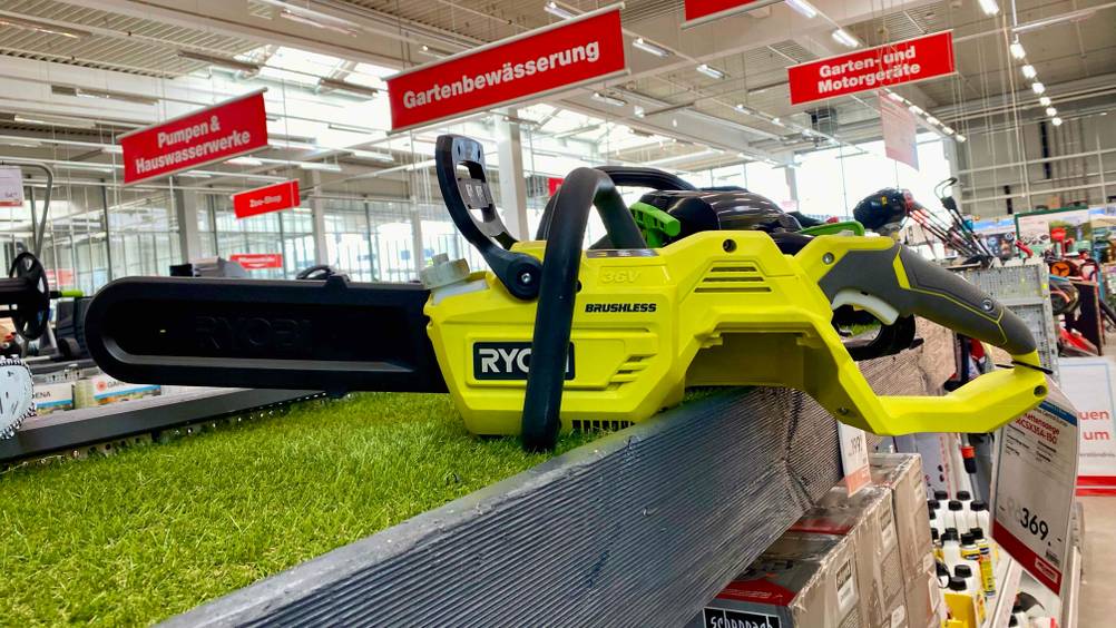 Akku-Kettensäge getestet: Seitenansicht eines Gerätes auf einem Verkaufsregal mit Kunstrasen, am Griff ein Preisschild.