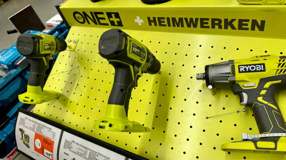 Ein Ryobi-Akkuschrauber im Test von hinten in einer gelben Fläche steckend.