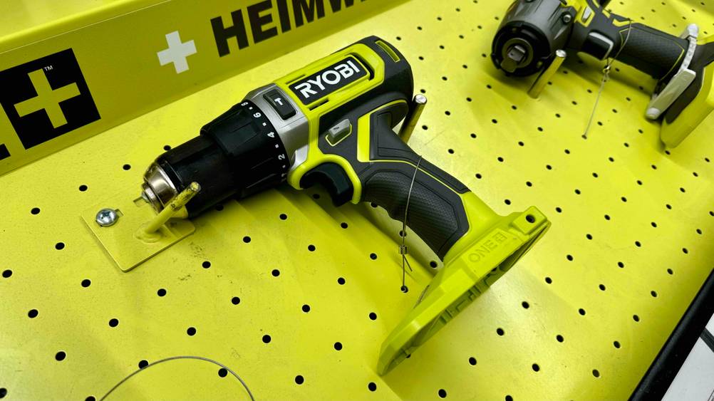 Auf einer gelben Fläche ist ein getesteter Ryobi-Akkuschrauber auf der Seite liegend befestigt.