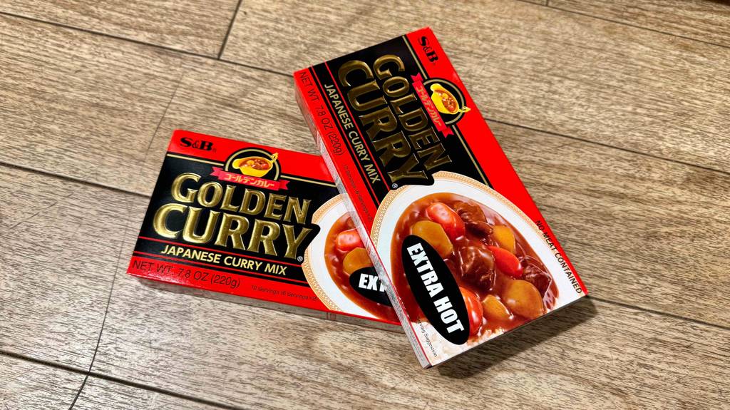 Japanisches getestetes goldenes Curry in zwei Packungen mit Würfeln liegt auf einer Holzfläche.
