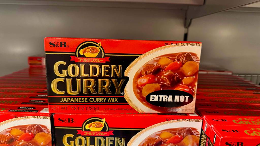Japanisches getestetes Golden Curry in einer Verpackung mit Würfeln steht auf einem Verkaufsregal.
