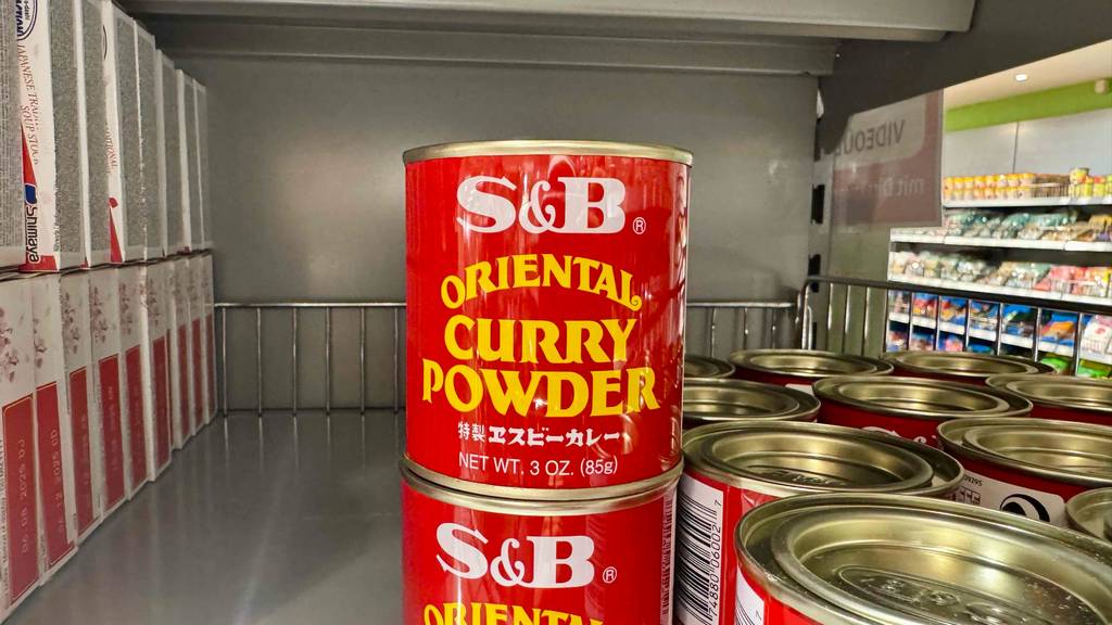 Eine rote Dose mit getestetem Currypulver steht auf einer weiteren Dose auf einem Regal im Supermarkt.