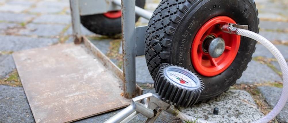 Reifen einer Sackkarre 250 kg im Test. Nahaufnahme eines Druckluftgeräts, das ein Reifen einer Sackkarre mit Luft versorgt.