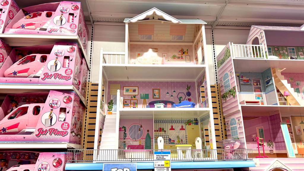 Das Holz-Puppenhaus im Test befindet sich zwischen weiteren Puppenstuben auf einem Ausstellungsregal.
