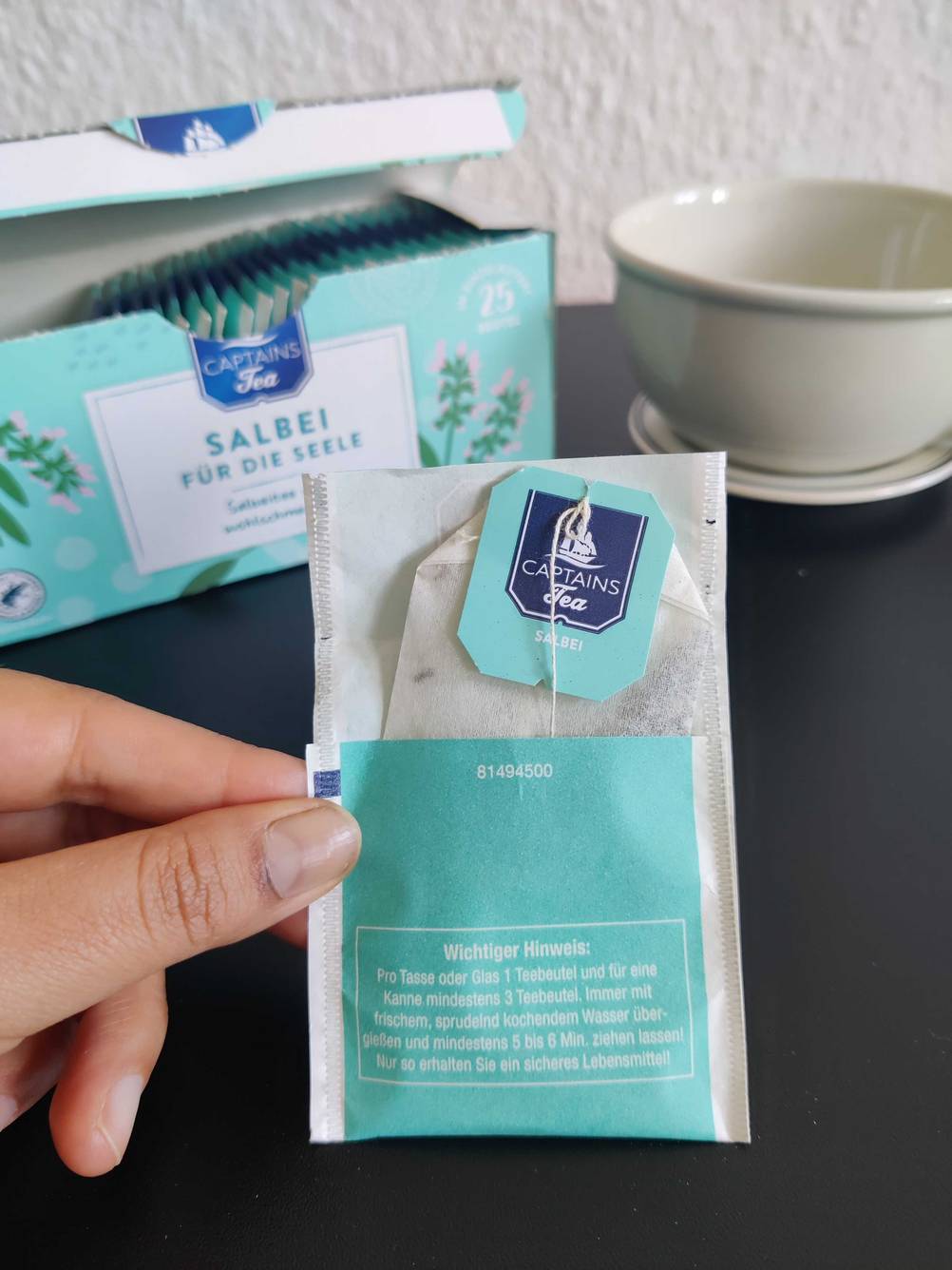 Ein Salbeitee im Test: Eine Hand hält eine geöffnete Teebeutel-Verpackung. 