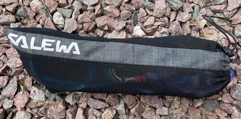 Nahaufnahme des Aufbewahrungsbeutels aus schwarzem Netzstoff eines Salewa Klettergurts im Test auf rötlichen Schottersteinen.