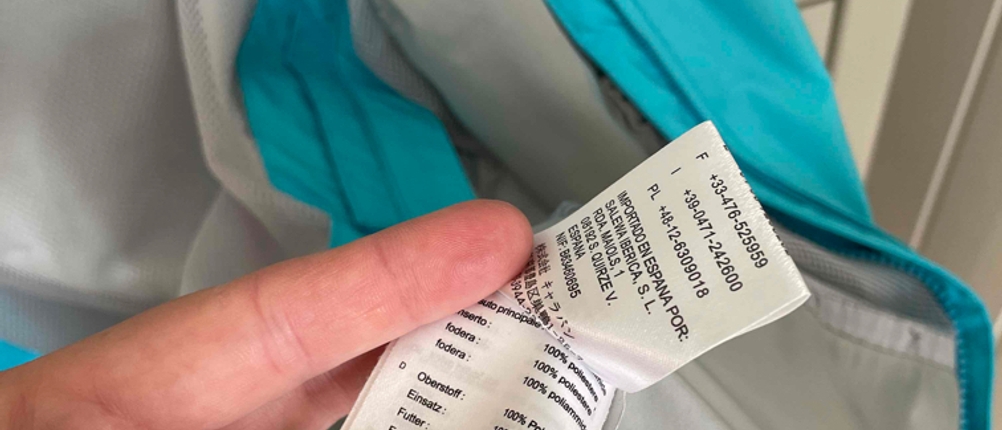 Hand zeigt das Etikett einer getesteten Regenjacke für Damen.