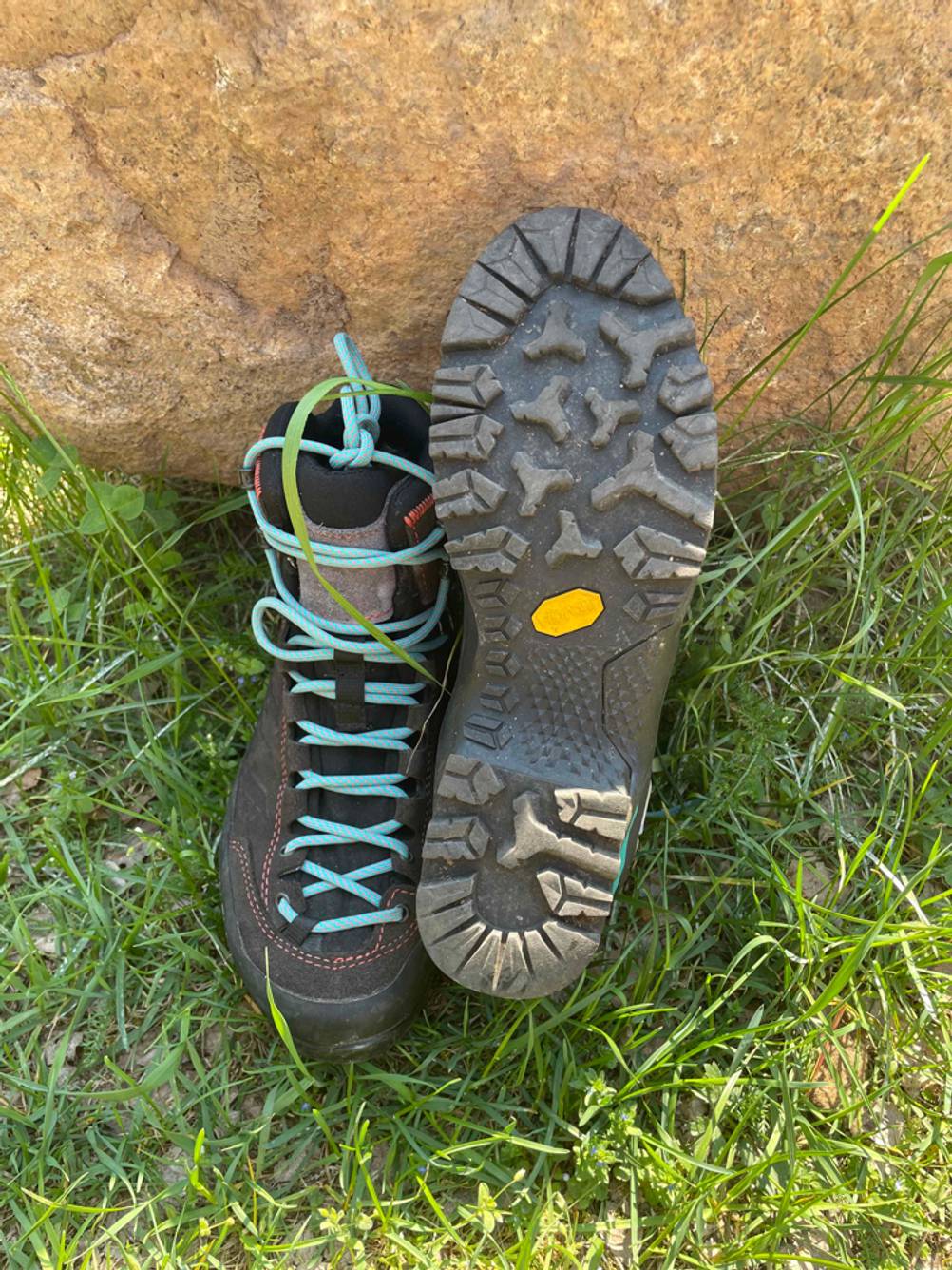 Im Test: Ein Paar Bergschuhe für Damen lehnen an einem Stein, ein Schuh von vorne, beim anderen ist die Sohle nach vorne gerichtet.