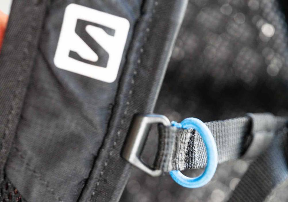Laufrucksack-Test: Detailansicht einer Einstell-Lasche mit hellblauem Gummiring von einem schwarzen Rucksack