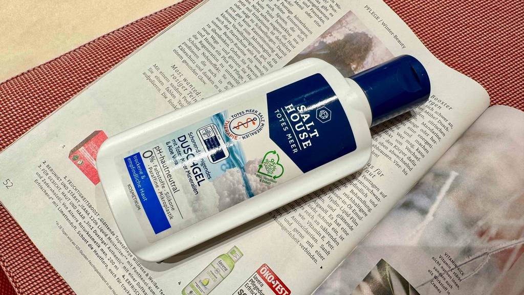 Im Test: Eine Flasche Totes-Meer-Duschgel liegt auf einer Zeitschrift mit Pflegeprodukten.