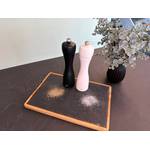 Zwei Salz- und Pfeffermühlen stehen neben gemahlenem Salz und Pfeffer auf einem Holzbrett mit Schieferplatte.