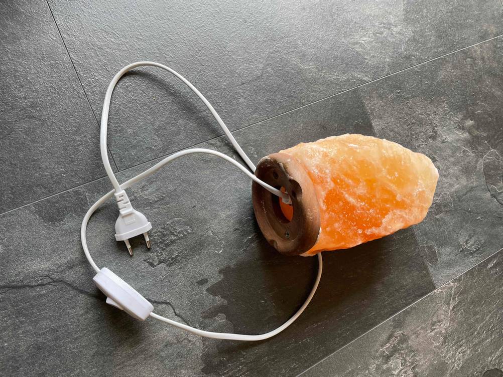 Eine getestete Salzlampe auf der Seite liegend mit dem Stromkabel aus der Öffnung kommend.