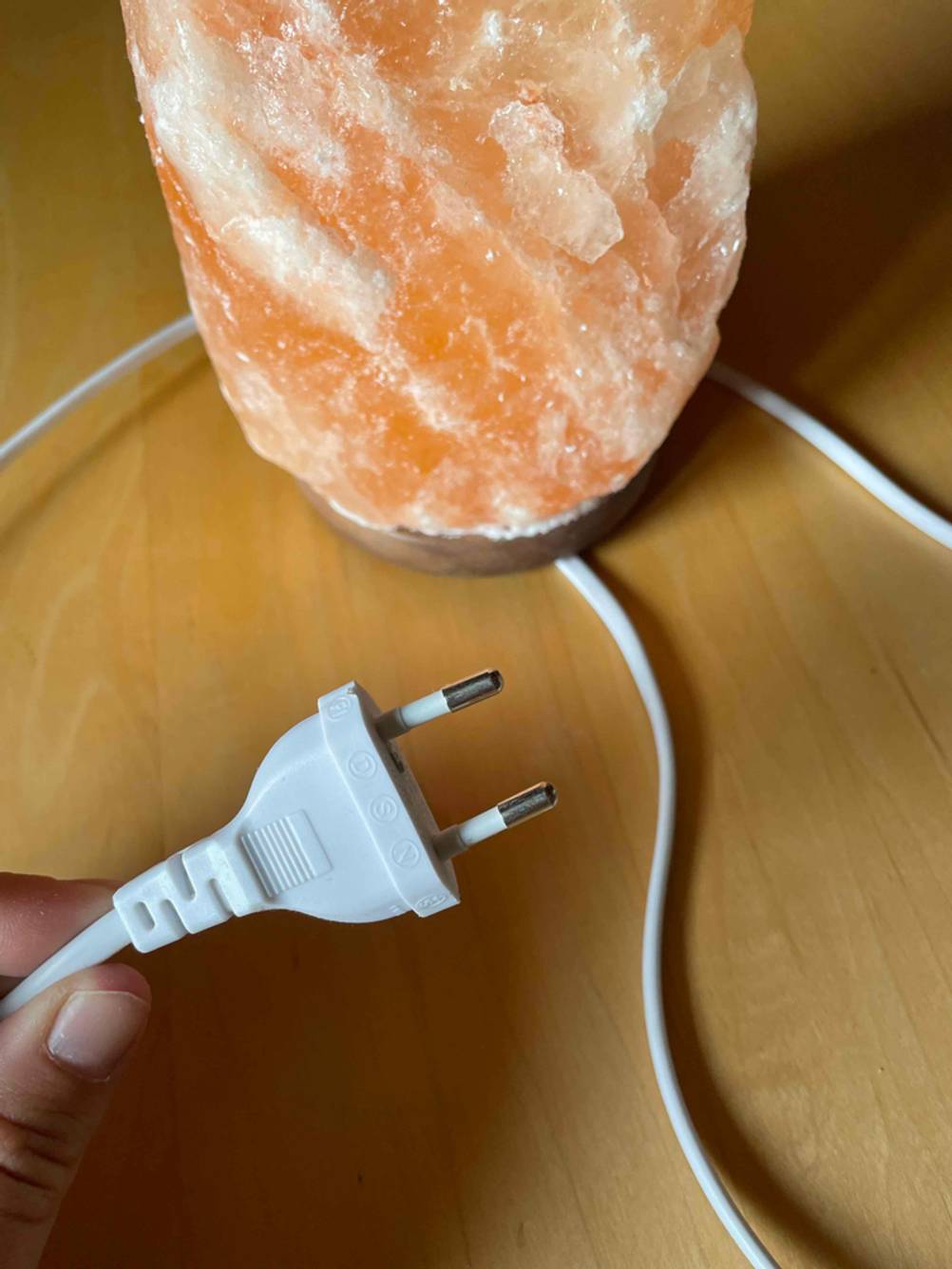 Salzlampe getestet: Nahaufnahme des Stromsteckers von zwei Fingern gehalten.