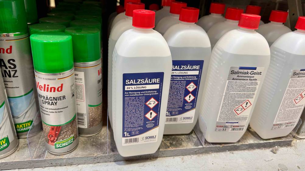 Mehrere Flaschen der getesteten Salzsäure neben anderen Produkten in einem Verkaufsregal.