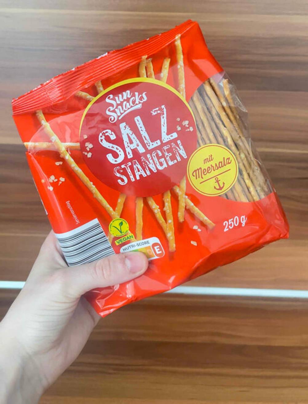 Eine Hand hält eine Packung Salzstangen zum testen.