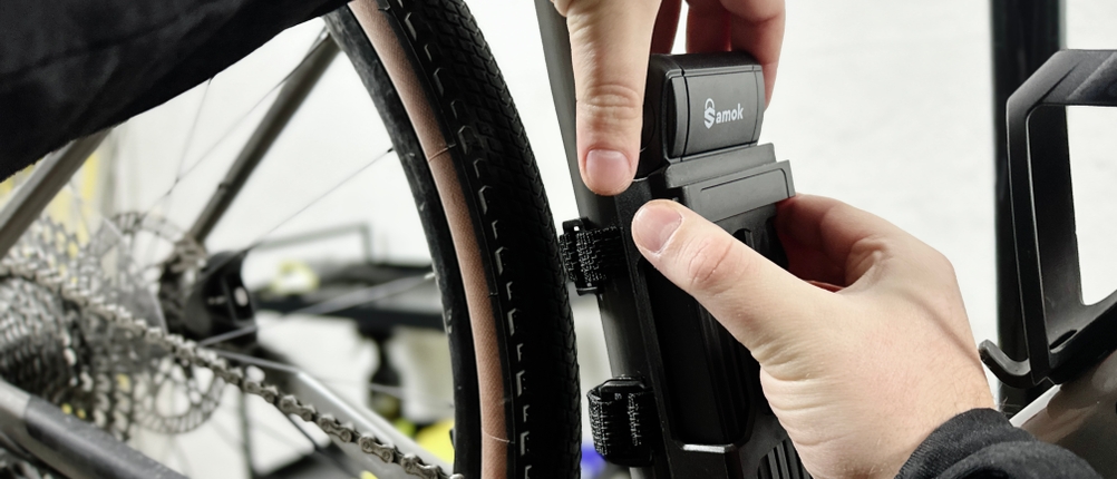 Das Samok-Klappradschloss wird aus der Halterung am Fahrradrahmen gezogen. Zwei Hände führen die Bewegung aus.