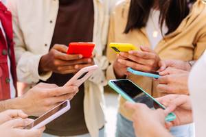 Gruppe junger Menschen mit Smartphones in der Hand.