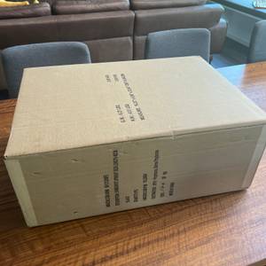 Der Karton des Samsonite Base Boost Upright liegt auf einem Holztisch.