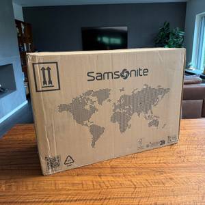 Der Karton des Samsonite S'Cure Spinner 75/28 steht auf einem Tisch.