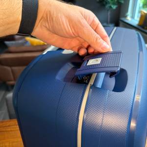 Eine Hand öffnet eine Verriegelung des Samsonite S'Cure Spinner 75/28.