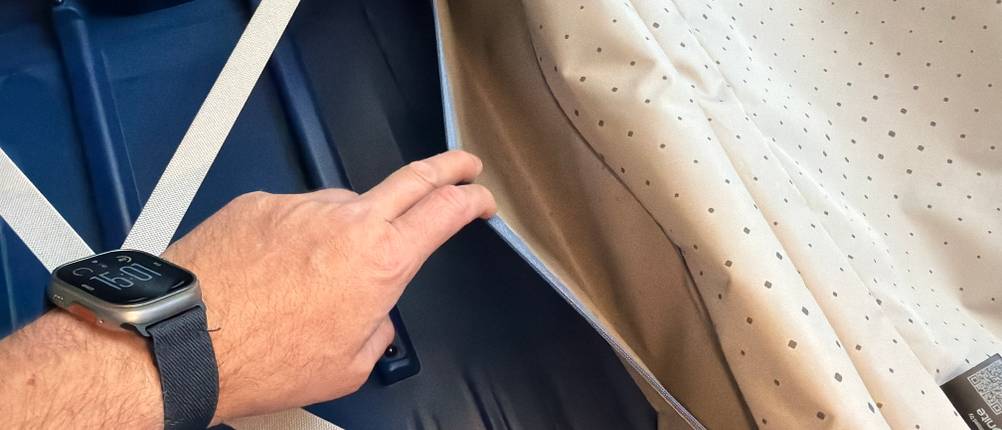 Eine Hand öffnet ein kleines Extrafach des Samsonite S'Cure Spinner 75/28.