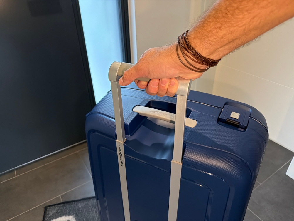 Eine Hand hält den ausgefahrenen Griff des Samsonite S'Cure Spinner 75/28 fest.