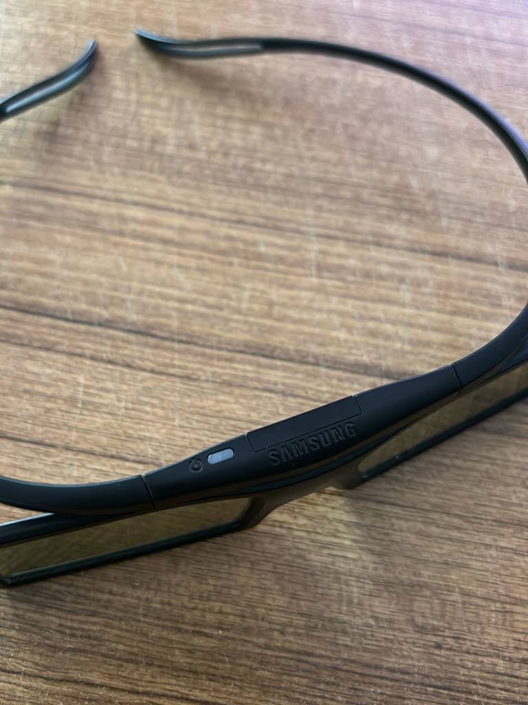 Detailansicht einer schwarzen Samsung 3D-Brille im Test vor einem Holzhintergrund.