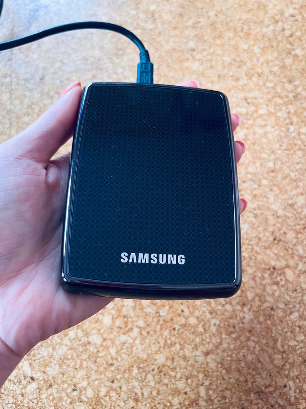 Im Test: Hand hält eine externe Festplatte 3-5 Zoll von Samsung.