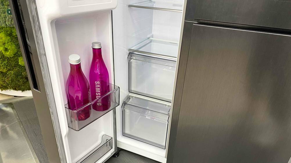 Im Test: Nahaufnahme der geöffneten linken Seite eines French-Door-Kühlschranks mit zwei Pinken Flaschen und mehreren Schubladen und Einlegeböden.