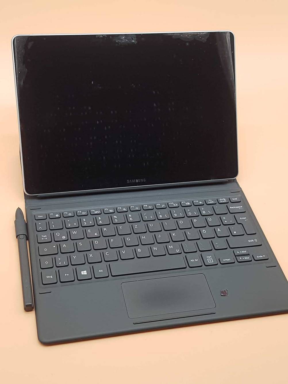 Getestet: Ein Samsung Galaxy Book mit Stift und Tastatur von vorne auf einer orangen Fläche stehend.