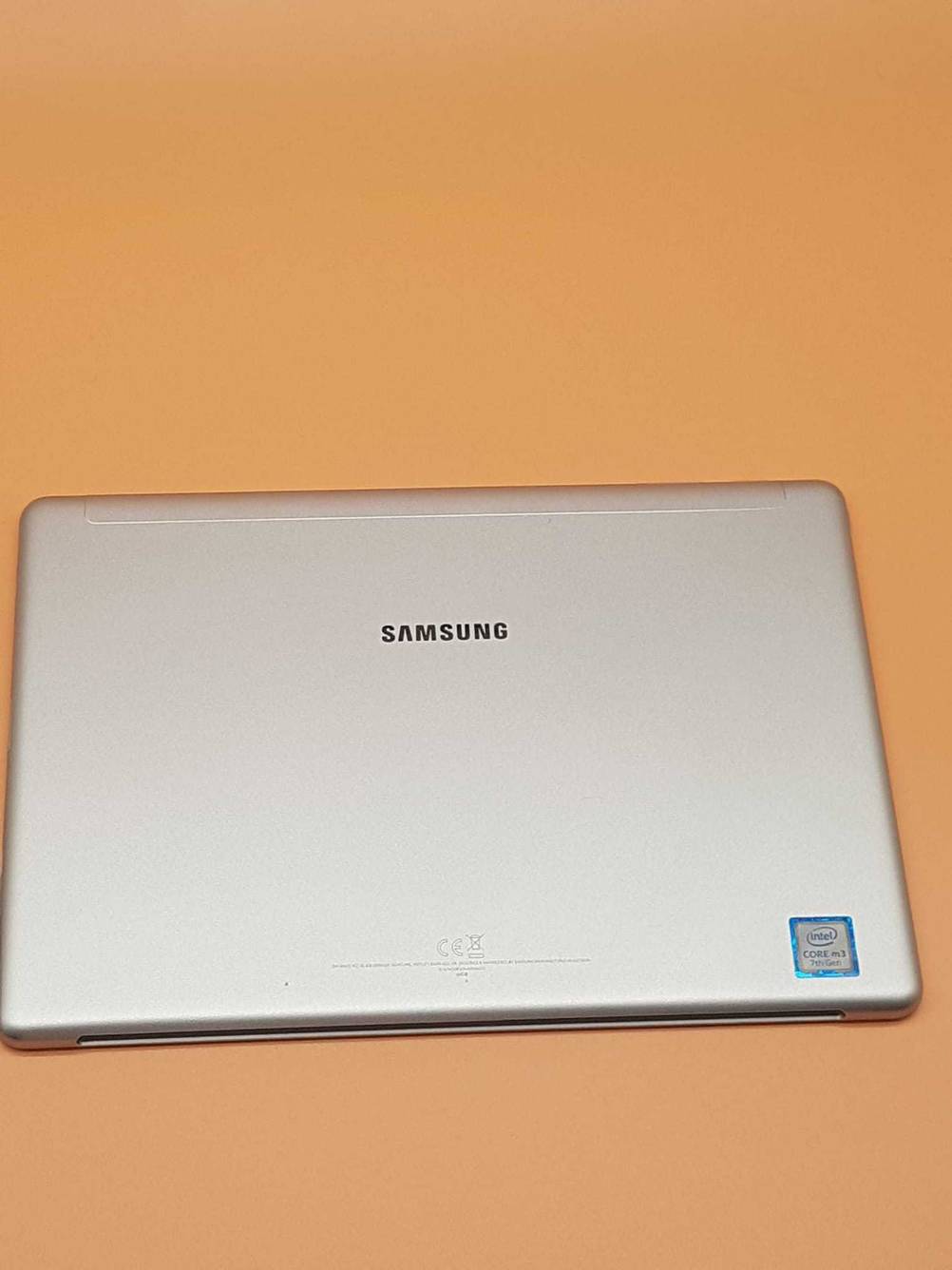 Im Test: Rückseite eines Samsung Galaxy Book von oben inklusive Logo auf einer orangen Fläche.