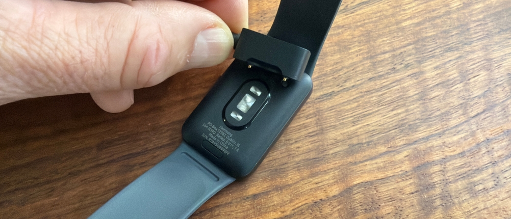 Eine Hand legt das Ladekabel auf die Samsung Galaxy Fit 3