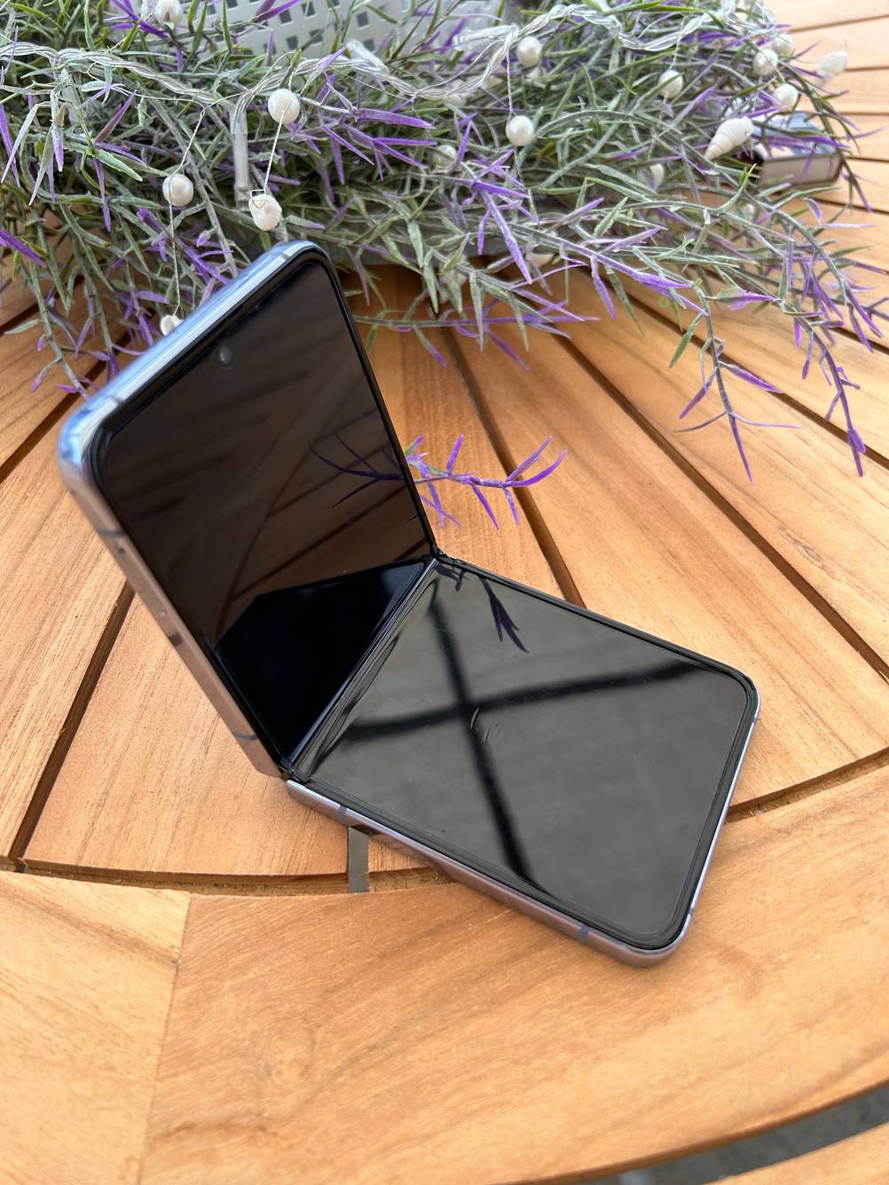 Klapphandy aufgeklappt auf einem Holztisch mit Blumen