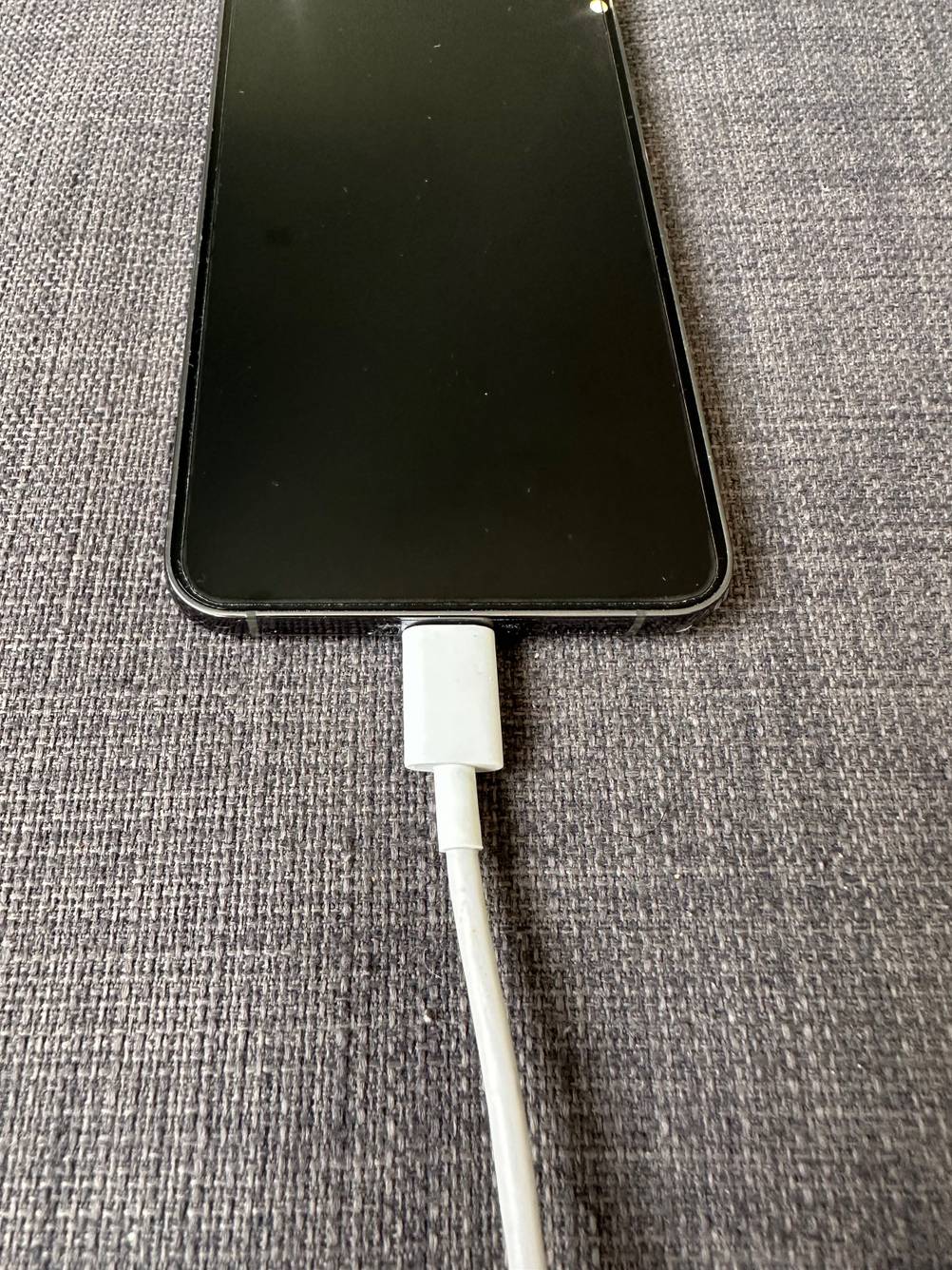 Im Test: Blick auf den unteren Teil eines Handys mit Samsung Galaxy S20-Panzerglas, angesteckt an ein Ladekabel.