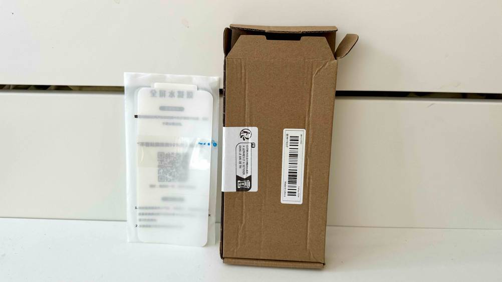 Samsung-Galaxy-S20-Plus-Panzerglas-Test: Ein Katon und ein verpacktes Glas lehnen an einer hellen Wand.