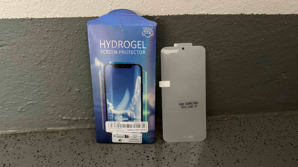 An einer Wand steht neben der Originalverpackung ein getestetetes Samsung-Galaxy-S20-Ultra-Panzerglas.