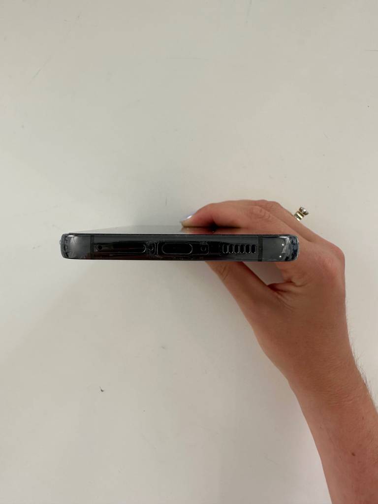 Samsung Galaxy S20 Panzerglas im Test: Hand hält ein Smartphone mit der unteren Seite nach vorn vor einer weißen Wand.
