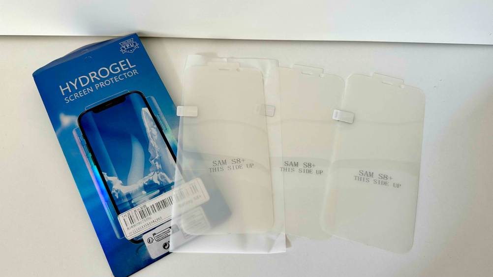 Samsung-Galaxy S8-Plus-Panzerglas getestet: Die Originalverpackung neben drei Gläsern auf einer hellen Fläche.
