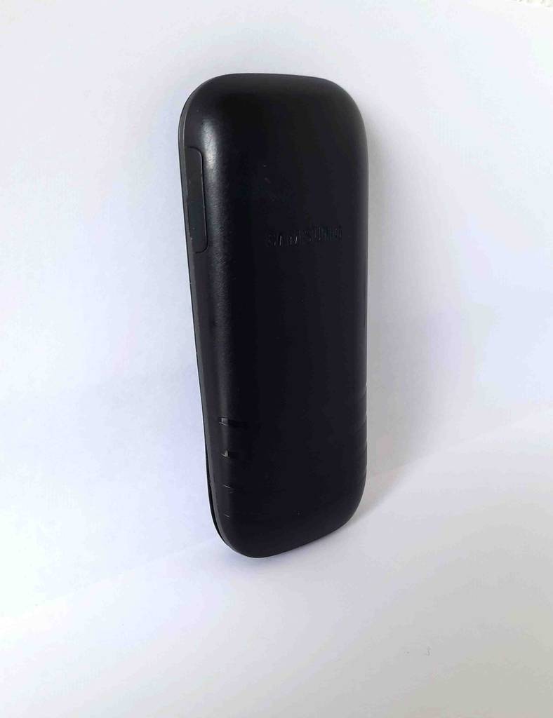 Ein schwarzes, getestetes Tastenhandy der Marke Samsung von hinten betrachtet.