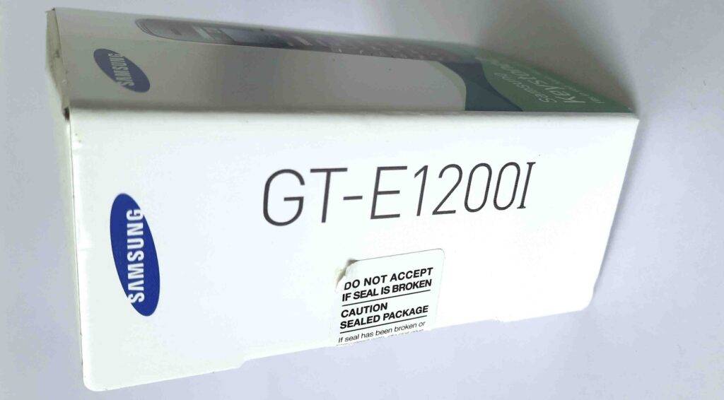 Detailansicht der weißen Verpackung mit Typen-Angabe eines getesteten Tastenhandys der Marke Samsung.