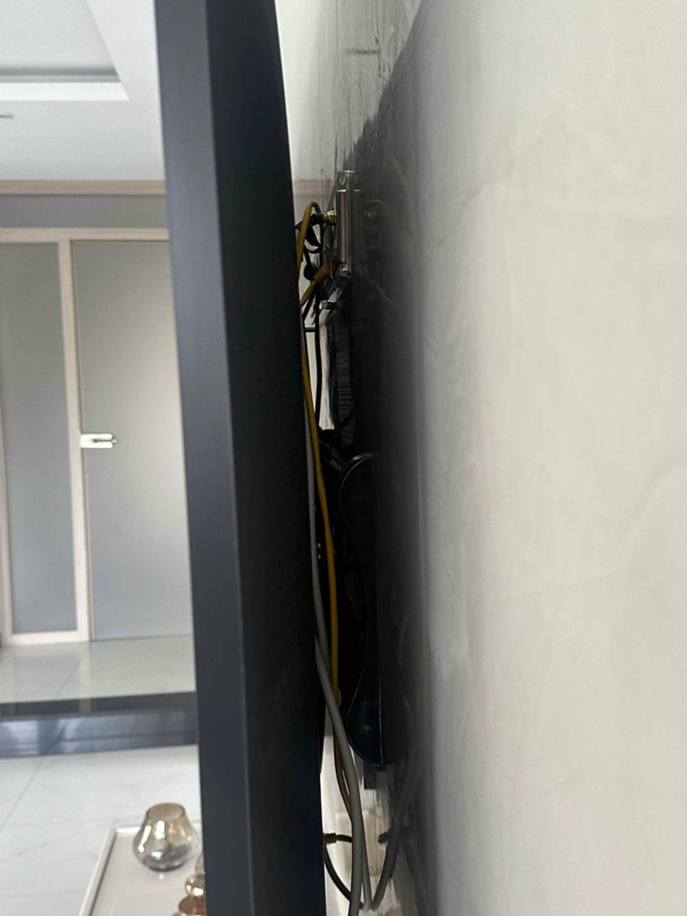 Im Test: Blick im Detail auf die Wandhalterung und Kabel an einem montierten 80-Zoll-Fernseher.