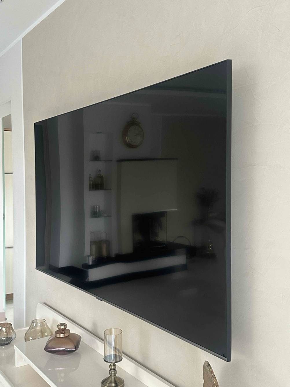 Blick von schräg vorn auf einen zum Testen an einer Wand montierten 80-Zoll-Fernseher.